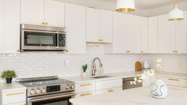 kitchen featuring sink, white cabinetry, hanging light fixtures, stainless steel appliances, and backsplash