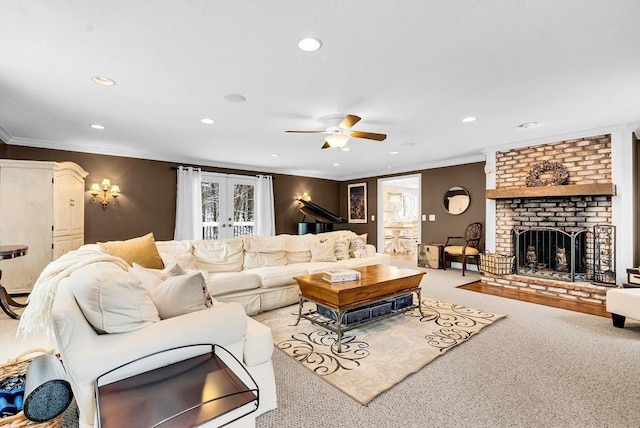 carpeted living room with ceiling fan, french doors, ornamental molding, and a fireplace