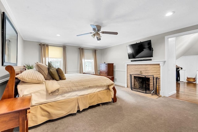 carpeted bedroom with ceiling fan, a brick fireplace, and ornamental molding