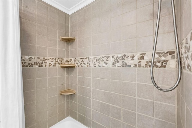 bathroom with tiled shower and crown molding