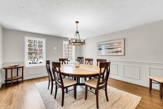 dining area featuring light wood-type flooring, a chandelier, and ornamental molding