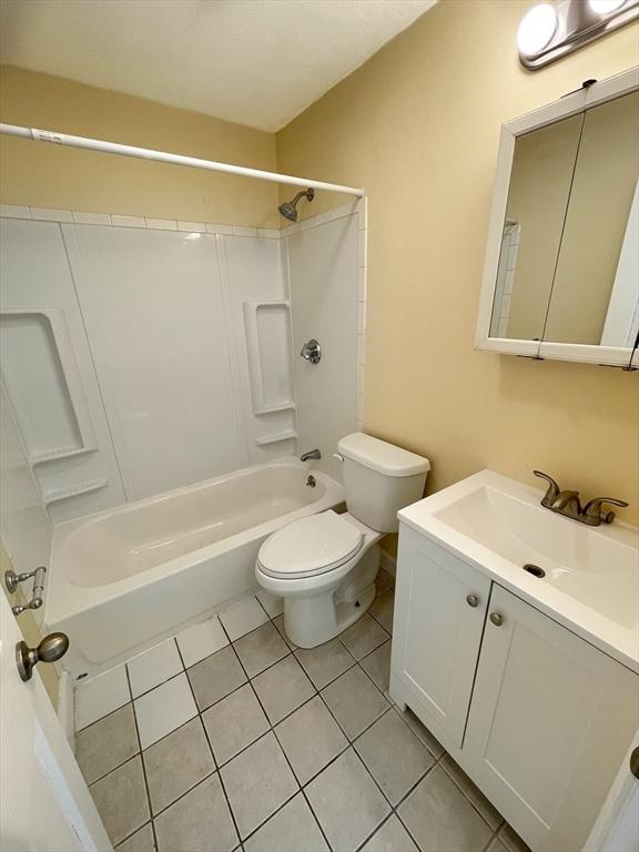 full bathroom with washtub / shower combination, vanity, toilet, and tile patterned flooring