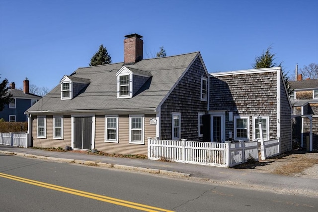 view of front of property featuring a fenced front yard and roof with shingles