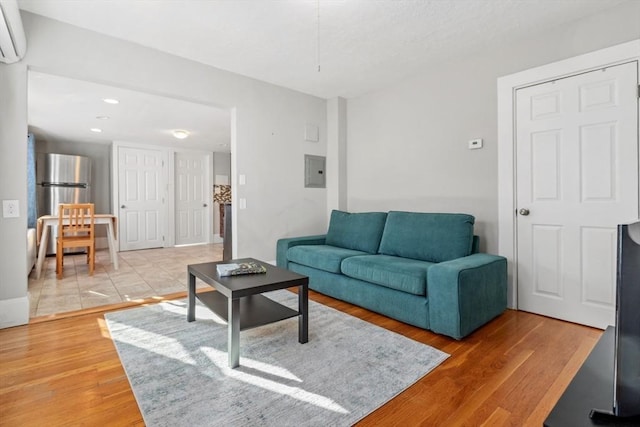 living room featuring light wood-type flooring, electric panel, an AC wall unit, and recessed lighting