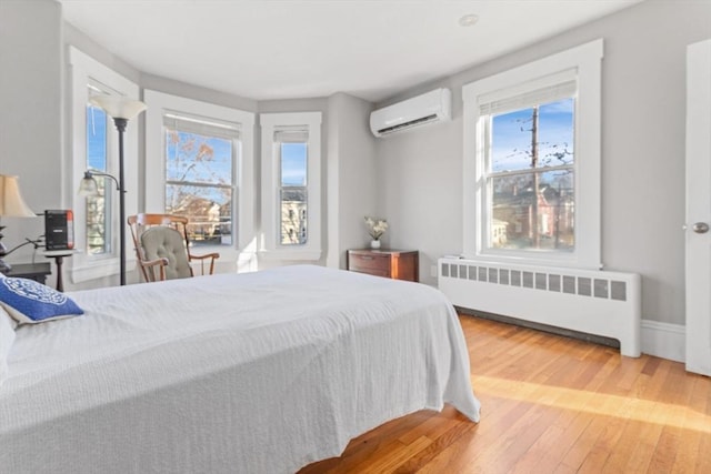 bedroom with wood-type flooring, radiator heating unit, and a wall unit AC