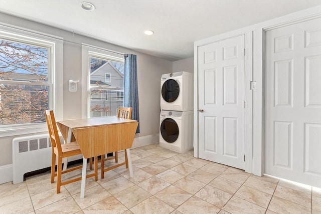 laundry room featuring stacked washer and dryer, laundry area, baseboards, radiator, and recessed lighting