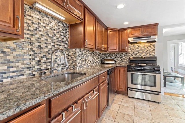 kitchen featuring brown cabinets, backsplash, appliances with stainless steel finishes, a sink, and under cabinet range hood