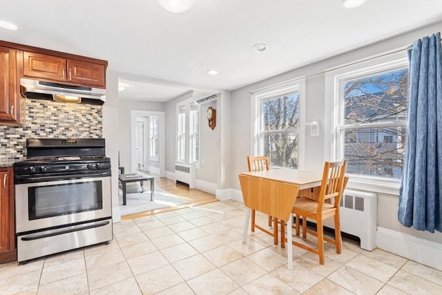 kitchen with tasteful backsplash, radiator, under cabinet range hood, and gas range