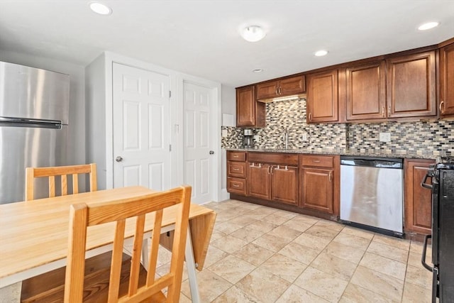 kitchen with appliances with stainless steel finishes, tasteful backsplash, and dark stone counters