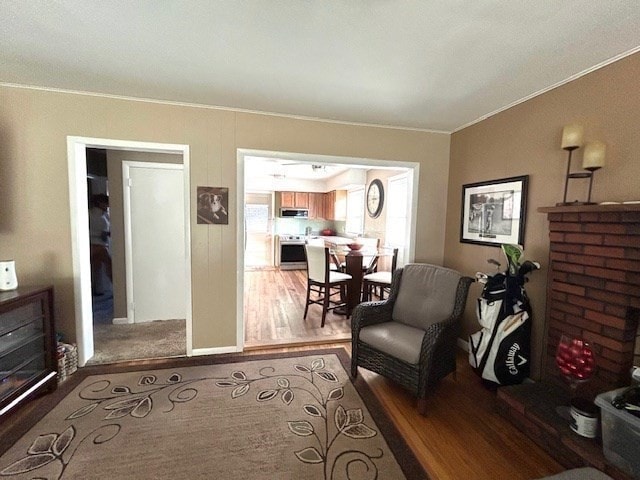 living room featuring a brick fireplace, hardwood / wood-style floors, and crown molding