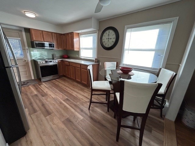 kitchen with ceiling fan, appliances with stainless steel finishes, decorative backsplash, and light hardwood / wood-style floors