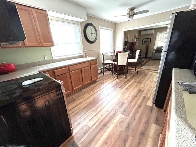 kitchen with a wall mounted AC, range, ceiling fan, light wood-type flooring, and fridge