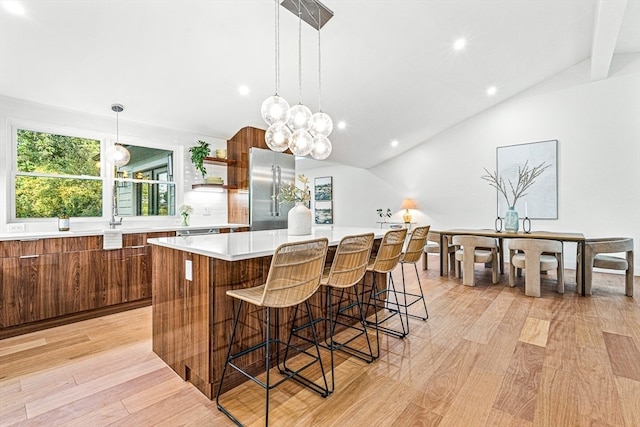 kitchen with light hardwood / wood-style floors, vaulted ceiling, a center island, and high end fridge