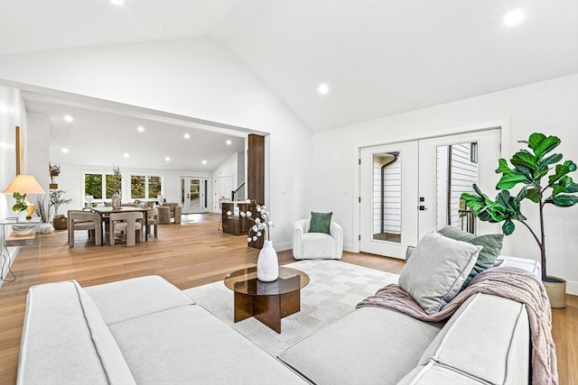 living room with light hardwood / wood-style floors, french doors, and high vaulted ceiling