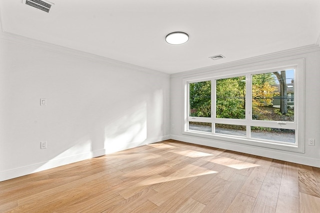 spare room featuring ornamental molding and light hardwood / wood-style flooring