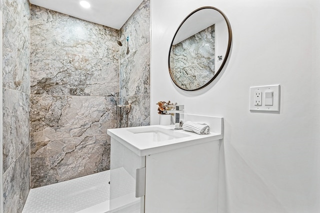 bathroom with a tile shower and vanity