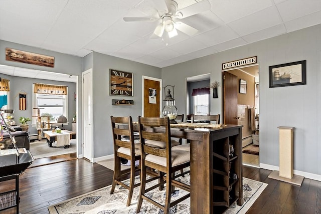 dining room with dark wood-type flooring, baseboards, and a ceiling fan