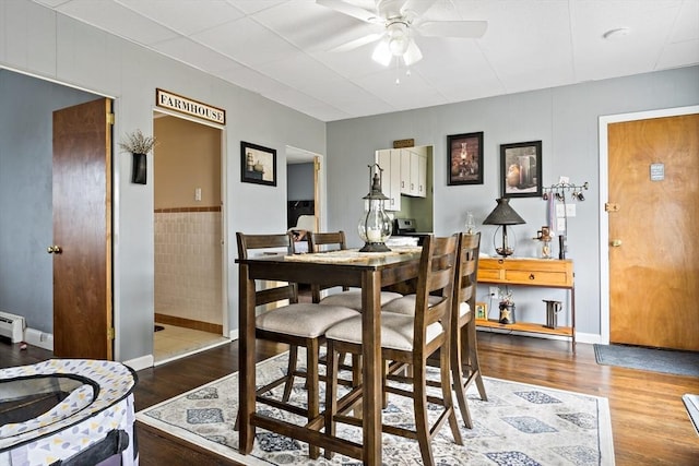 dining area with ceiling fan, a baseboard heating unit, and wood finished floors