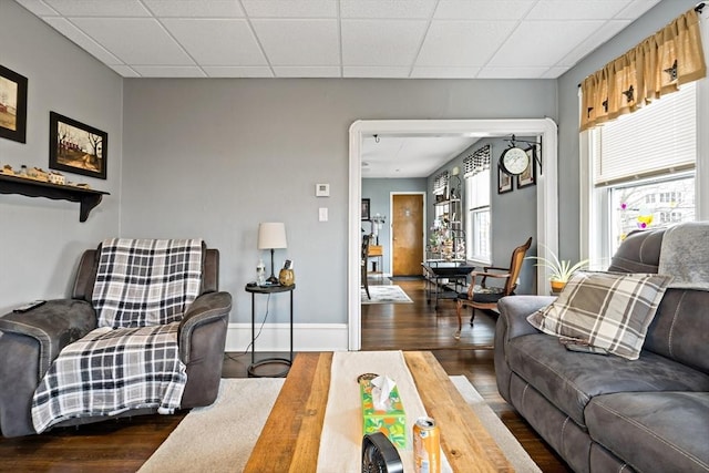 living area featuring wood finished floors, a paneled ceiling, and baseboards