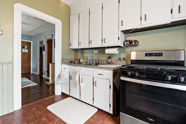 kitchen featuring tasteful backsplash, white cabinetry, a sink, and gas stove