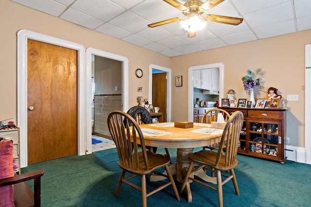 carpeted dining space with a paneled ceiling and ceiling fan