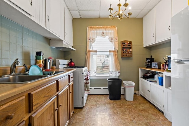 kitchen featuring a paneled ceiling, a baseboard heating unit, a sink, white appliances, and under cabinet range hood