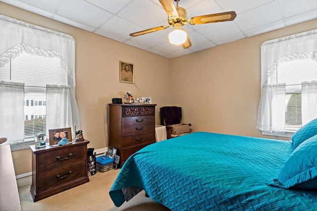 bedroom with ceiling fan, carpet floors, and a drop ceiling