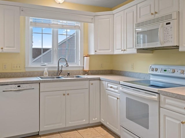 kitchen with white appliances, a sink, white cabinetry, light countertops, and light tile patterned floors