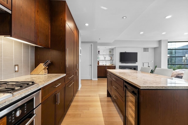 kitchen with oven, a kitchen breakfast bar, wine cooler, light hardwood / wood-style flooring, and light stone countertops