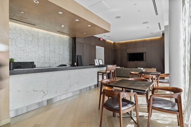 dining space featuring light hardwood / wood-style flooring and wooden walls