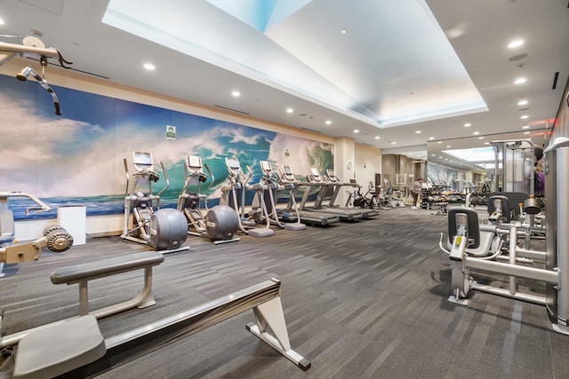 exercise room featuring carpet flooring and a tray ceiling