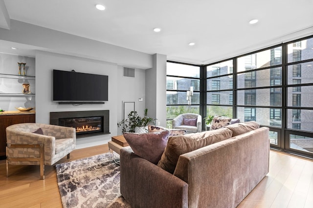 living room featuring light wood-type flooring and a wall of windows