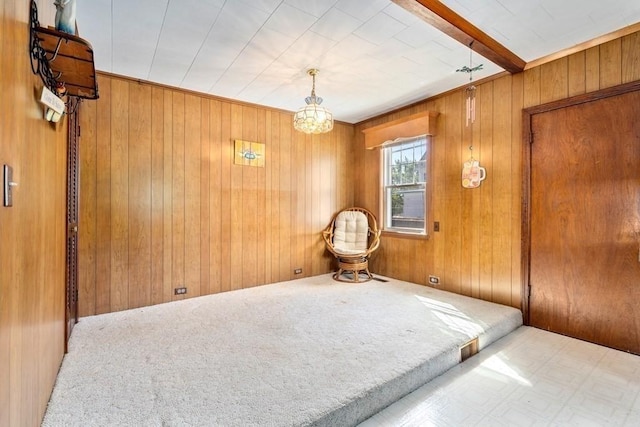 unfurnished bedroom featuring beamed ceiling, carpet, and wood walls