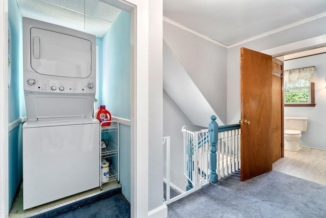 washroom featuring crown molding, stacked washer and clothes dryer, and carpet flooring