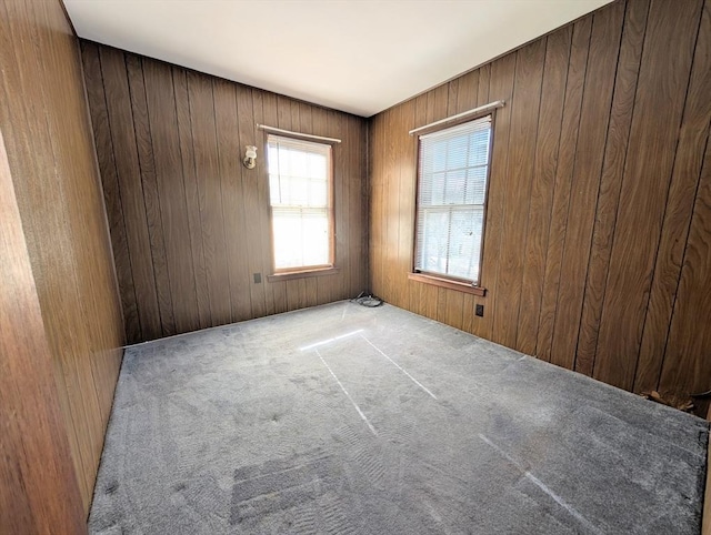 unfurnished room featuring light colored carpet and wood walls