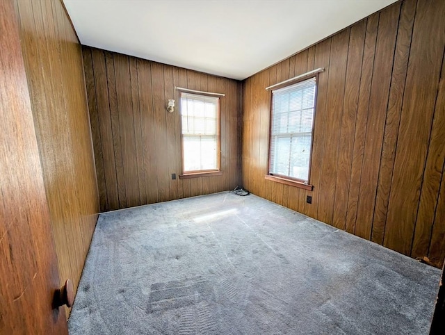 carpeted spare room with wooden walls