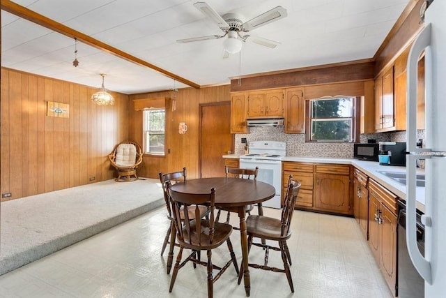 kitchen featuring electric range, wooden walls, decorative light fixtures, and a healthy amount of sunlight