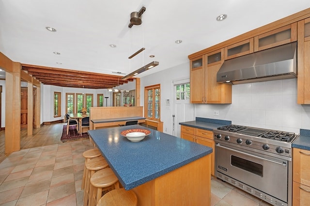 kitchen featuring a center island, premium stove, extractor fan, and a healthy amount of sunlight