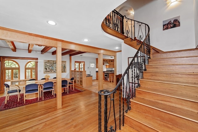 stairs with wood-type flooring and beamed ceiling