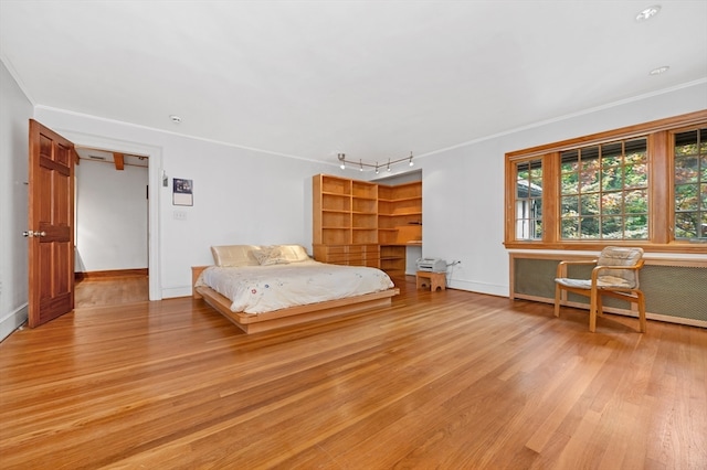 unfurnished bedroom featuring ornamental molding, light hardwood / wood-style floors, and rail lighting