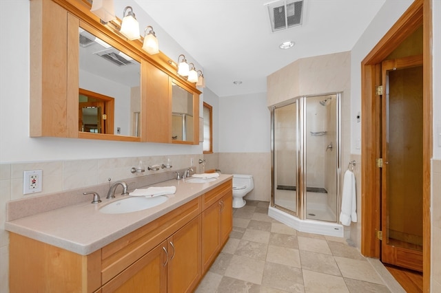 bathroom with tile walls, vanity, an enclosed shower, toilet, and tile patterned floors