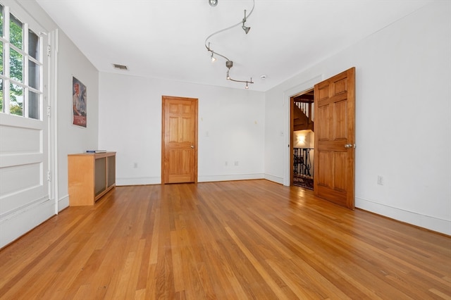 unfurnished living room featuring light hardwood / wood-style flooring and rail lighting