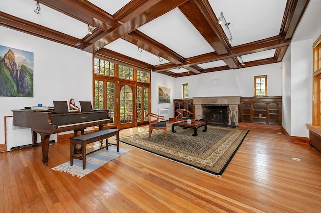 sitting room with light wood-type flooring, a healthy amount of sunlight, a large fireplace, and beamed ceiling