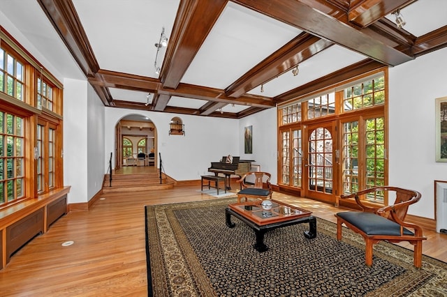 sitting room featuring beamed ceiling, french doors, light hardwood / wood-style flooring, coffered ceiling, and crown molding