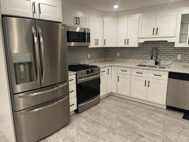 kitchen with stainless steel appliances, a sink, light stone countertops, and white cabinets