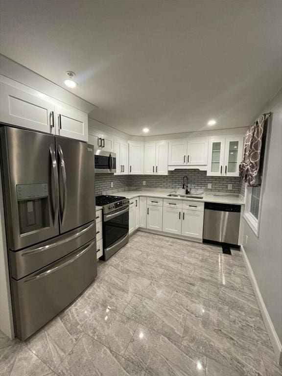 kitchen featuring appliances with stainless steel finishes, a sink, white cabinetry, and tasteful backsplash