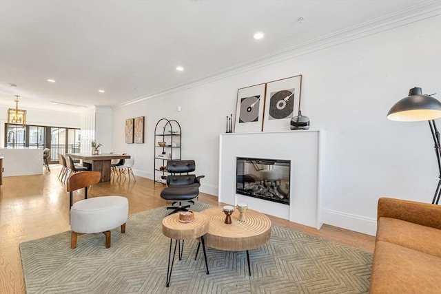 living area with baseboards, a glass covered fireplace, light wood-style flooring, crown molding, and recessed lighting