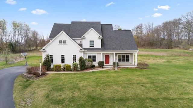 view of front of house featuring a porch, roof with shingles, and a front yard