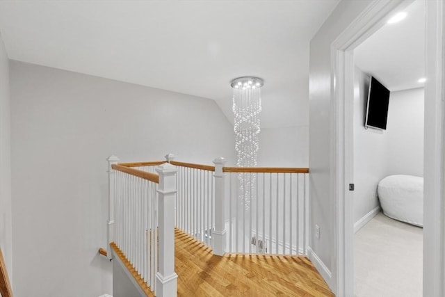 corridor with baseboards, wood finished floors, and an upstairs landing