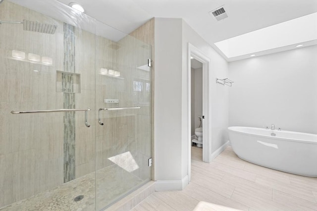 bathroom featuring visible vents, a freestanding bath, a stall shower, baseboards, and toilet